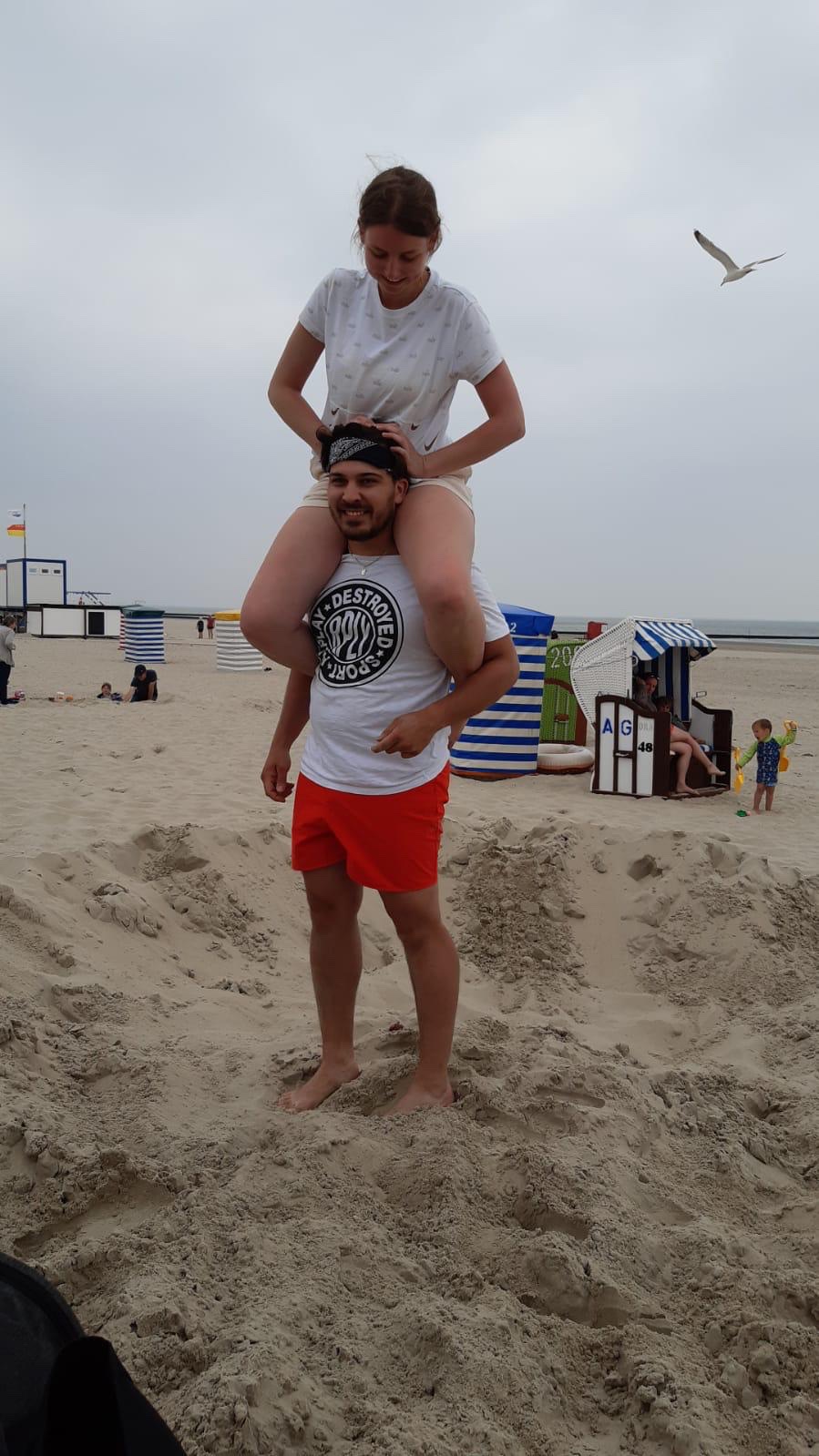 Luca trägt Caro im Urlaub mit Familie Plescher am Strand auf den Schultern